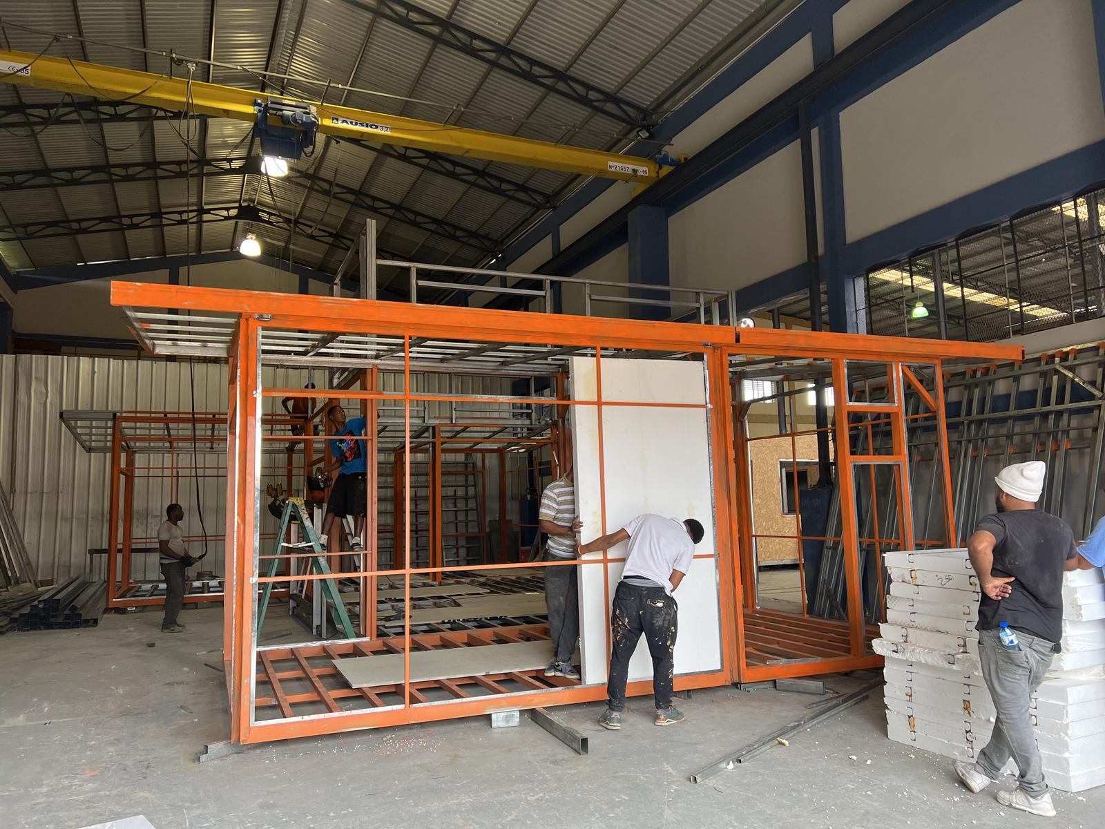 Workers fitting wall panels to steel frames in the plant