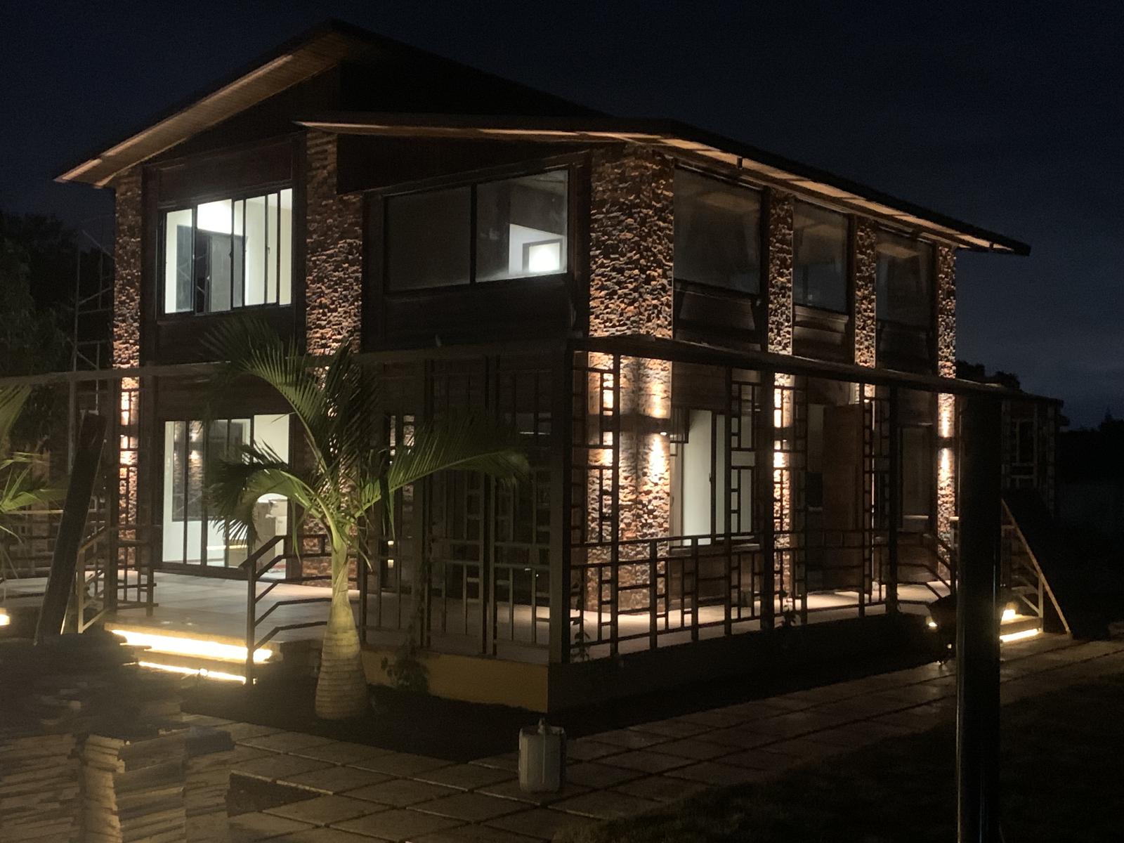 Two-storey stone-clad home lit at night