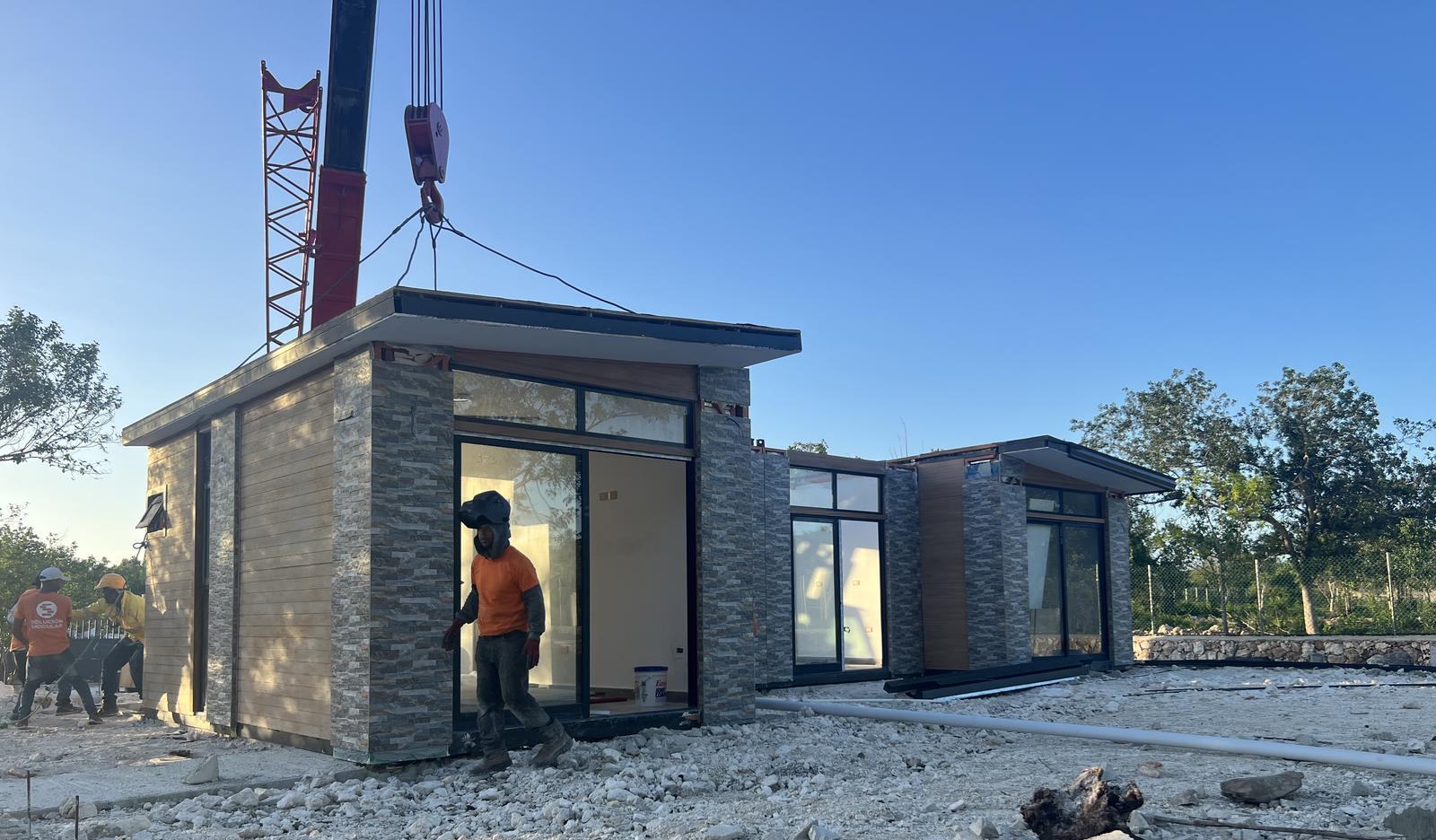Crane setting a finished home section on its foundation