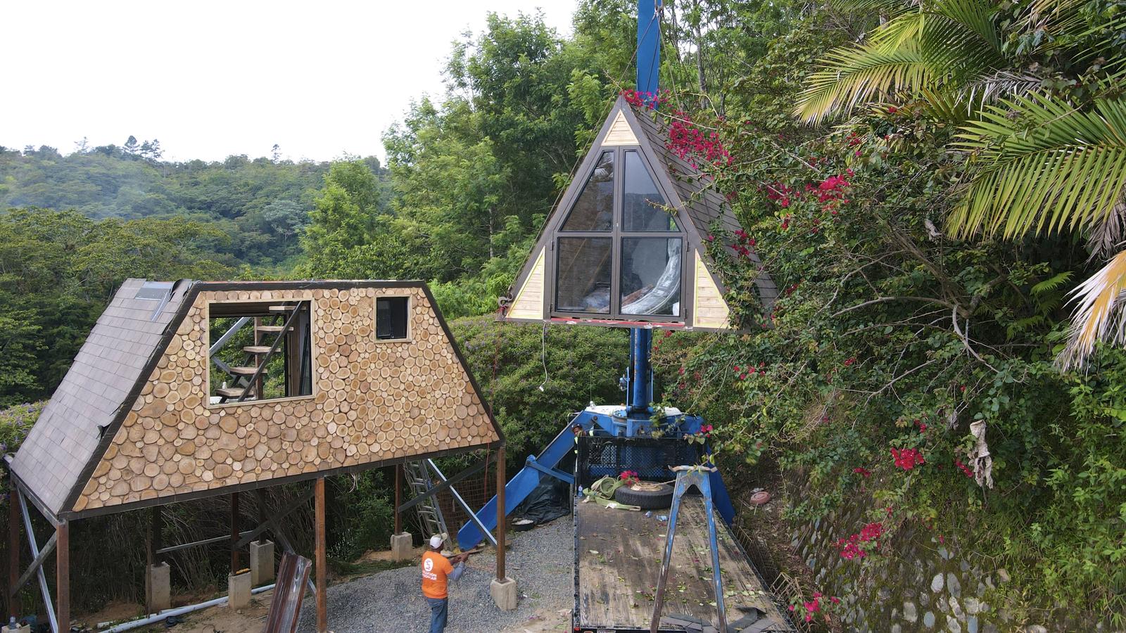 Crane lifting a finished A-frame section into a garden
